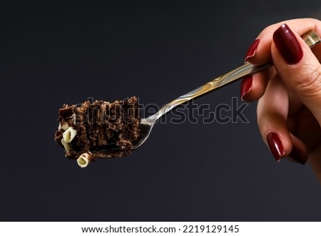 A piece of chocolate dessert cake on a fork on the background of a female hand. Shallow depth of field