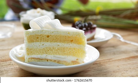 A piece of coconut cake in dish on wooden Table, close up. Coconut cake decorated on a sliced ​​coconut on a white plate. Delicious bakery And provide high calorie.
