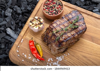 Piece Of Cooked Rump Steak With Spices Served On Wooden Cutting Board