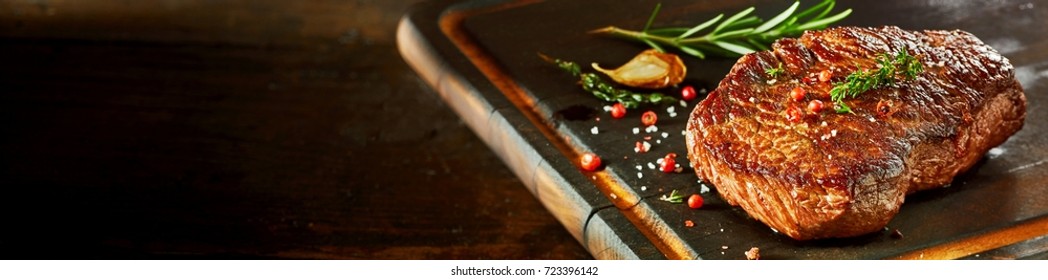 Piece Of Cooked Rump Steak With Spices Served On Wooden Cutting Board