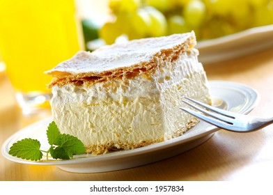 Piece of cream and custard pastry with melissa and grapes