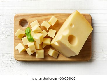 Piece And Cubes Of Swiss Cheese On Cutting Board. From Top View