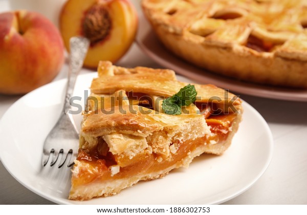 Piece of delicious fresh peach pie served on
white table, closeup