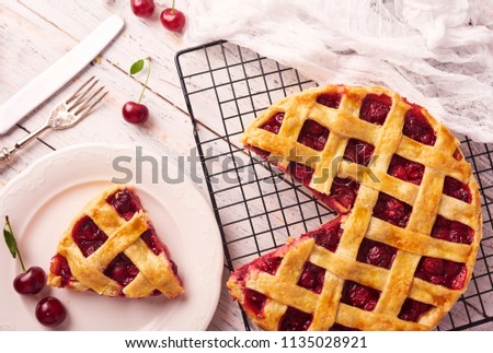 Piece of Delicious Homemade Cherry Pie with a Flaky Crust on rustic wooden white background