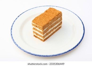 A piece of delicious layered honey cake, highlighted on a white background. A piece of honey cake on a white plate. Isolated object.