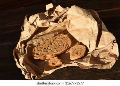 Piece Of Dried Bread On Crumpled Paper On Dark Background. Isolated. Need Food. War, Hunger, Poverty, Economic Crisis And Social Inequality.