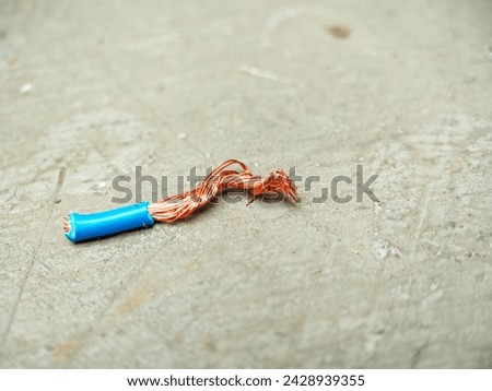 piece of electric wired cable wrapped in blue plastic isolated with grey background