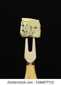 A Piece Of French Blue Cheese On A Fork On A Black Background. Close-up