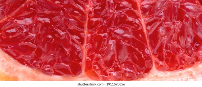 Piece of fresh grapefruit with juicy red pulp cut in half macro shot