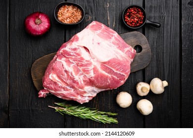 Piece of fresh raw pork from the neck set, with ingredients and herbs, on black wooden table background, top view flat lay