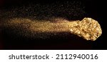 Piece of gold or golden nugget with visible gold shining comet tail ath the dark background. 