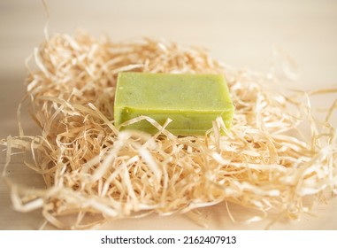 A Piece Of Green Soap Lies On Wrapping Paper, On A Wooden Table Surface. Hygiene, Soap Production, Supply Disruption, Shortages