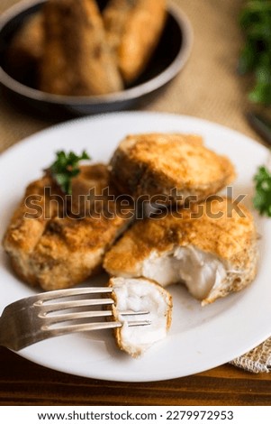 A piece of hake fish fried in a crispy crust, in a plate on a wooden table. Foto stock © 