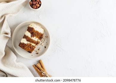 A piece of homemade carrot cake with cream, nuts and cinnamon on a plate. Horizontal orientation, top view, copy space.