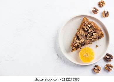 A piece of homemade mandarin pie with walnuts in a plate. Sugar, gluten and lactose free, vegan. Horizontal orientation, copy space, top view.