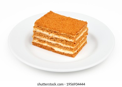 Piece of honey cake in a plate, isolated on a white background