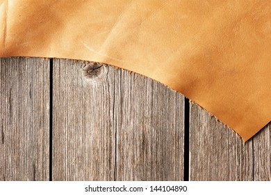 Piece of leather over wooden background