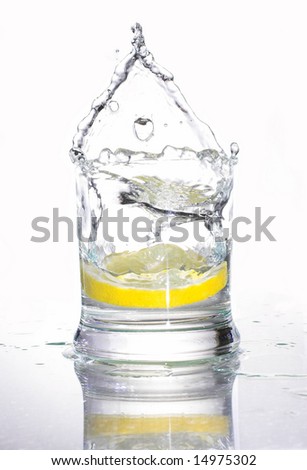piece of lemon falling into a glass of water