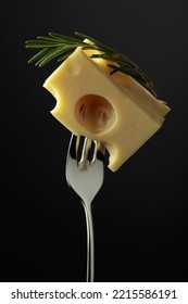 Piece of Maasdam cheese with rosemary on a black background. - Shutterstock ID 2215586191