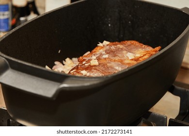 Piece Of Meat Is Fried With Onions In Rectangular Cooking Pot Over Fire On Gas Stove