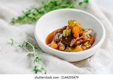 A piece of meat with stewed vegetables cut into cubes. Zucchini, pumpkin and potatoes. Snack in a small white bowl. ?opy space.