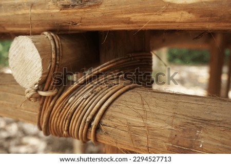 A piece of natural rope is tied in a knot around a wooden pole
