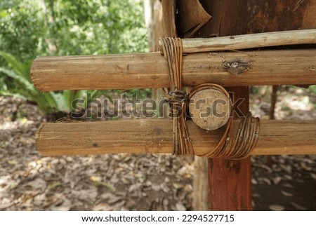 A piece of natural rope is tied in a knot around a wooden pole