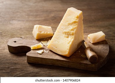 piece of parmesan cheese on a wooden board - Shutterstock ID 1407906824