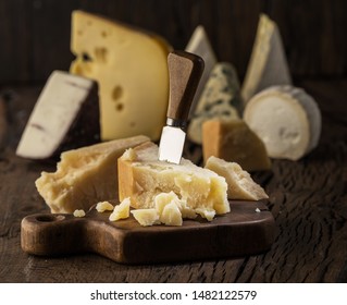 Piece of Parmesan cheese  on the wooden board. Assortment of different cheeses at the background. - Powered by Shutterstock