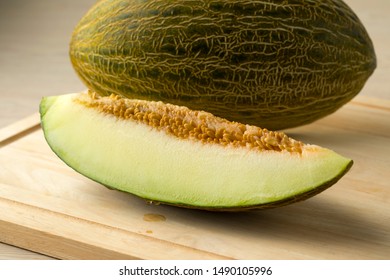 Piece of Piel de sapo melon and seed close up with a whole one at the background