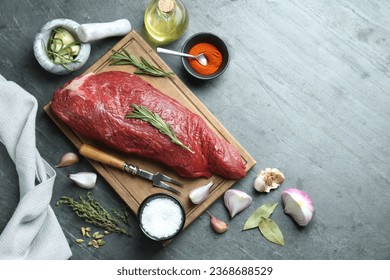 Piece of raw beef meat and spices on grey table, flat lay. Space for text - Shutterstock ID 2368688529