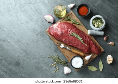 Piece of raw beef meat and spices on grey table, flat lay. Space for text - Shutterstock ID 2368688531
