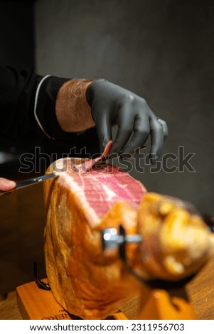Piece of raw ham, being cut into chips and served to harmonize with wines.