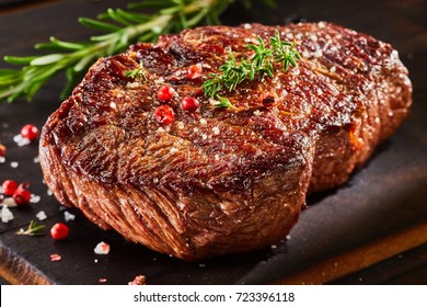Piece of roast beef with spices served on wooden cutting board