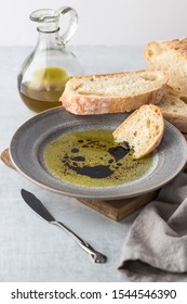 A piece of rustic bread dipped into balsamic vinegar and olive oil with a bottle of olive oil in behind.