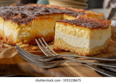 A Piece Of Rustic And Old German Sheet Cake Called Eierschecke Served On A Wooden Board On Kitchen Table