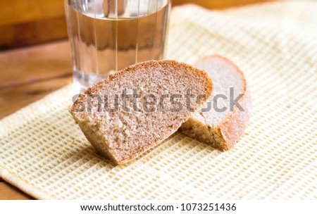 A piece of rye bread against the background of a glass of vodka