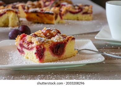 Piece Of Sheet Cake With Fruits And  Crumbles On A White Plate With Fork And A Cup Of Coffee