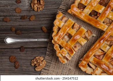 A piece of sliced apple pie with cinnamon and nuts on metal spatula on vintage wooden background texture. Top view