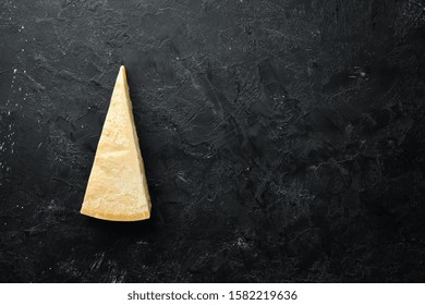 Piece of solid cheese on a black stone background. Parmesan. Top view. Free space for your text. - Powered by Shutterstock