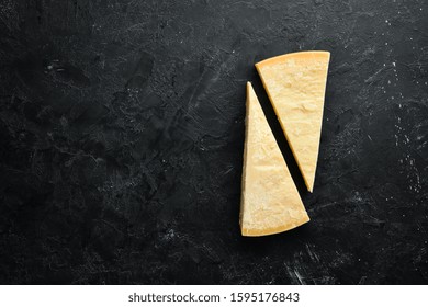 Piece of solid cheese on a black stone background. Parmesan. Top view. Free space for your text. - Powered by Shutterstock