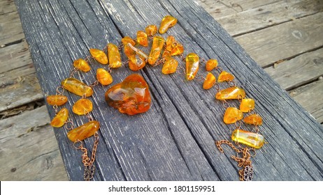 A piece of sparkling Baltic yellow raw natural amber and a wonderful amber necklace on an old, weathered wooden bench in the abandoned ruined boat.