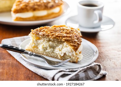 Piece of sweet almond cake on plate. Pie with cream and almonds.