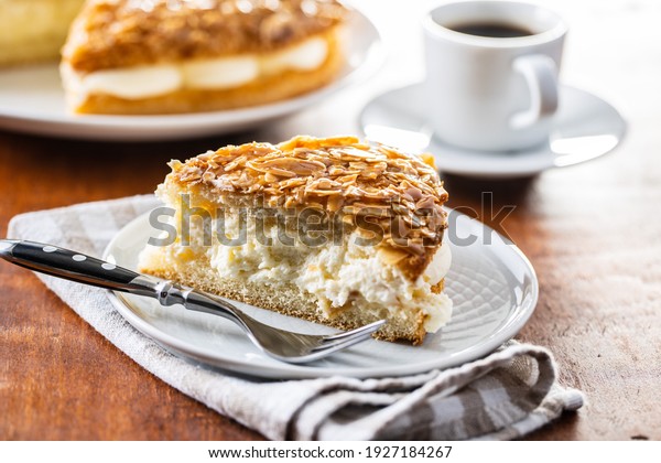 Piece of sweet almond cake on plate. Pie with\
cream and almonds.