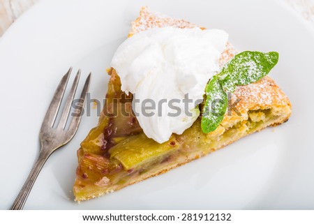 Piece of sweet cake with rhubarb, whipped cream and fresh mint