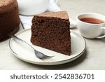 Piece of tasty chocolate sponge cake served on light table, closeup