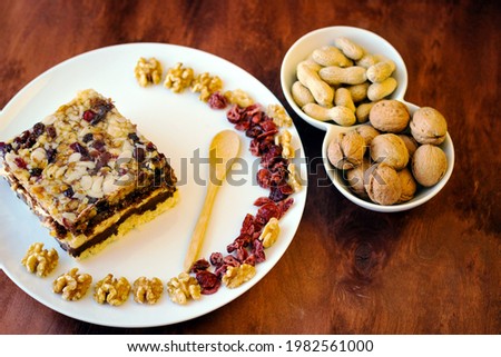 Piece of tasty chocolate-nut cake on a white plate. Walnuts and wooden spoon stand nearby Stock foto © 