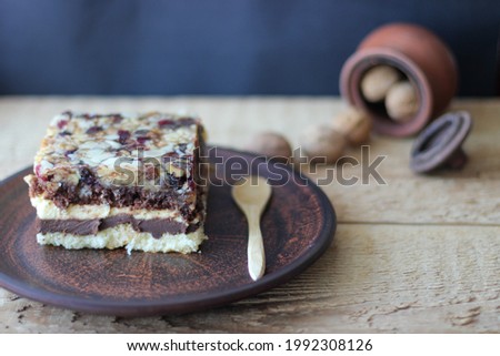 Piece of tasty chocolate-nut cake on a clay plate. Walnuts and wooden spoon stand nearby Stock foto © 