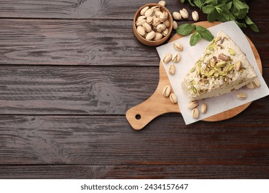 Pieza de sabrosa halva con pistachos y menta sobre mesa de madera, puesta plana. Espacio para texto