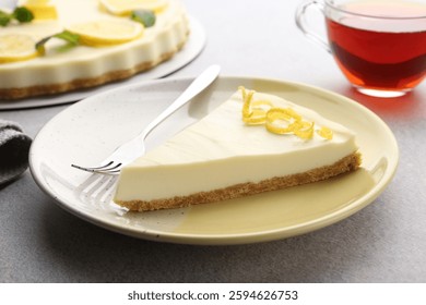 Piece of tasty lemon cheesecake and fork on grey textured table, closeup